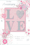 This anniversary card captures the gentleness of a long, shared journey, its design woven from soft pastel pinks, pearly whites, and silvery greys that echo the calm atmosphere of Northwood's tree-lined avenues. The focal point is the word LOVE, created in raised, glitter-soft letters that glimmer subtly under the light. In a charming twist, the letter O is replaced with a shimmering heart rendered in textured silver, making it look like a tiny keepsake nestled among the letters. The embossed glitter adds a tactile richness, suggesting the same care you might feel in the touch of a loved one's hand. Encircling this centrepiece, delicate flowers in shades of blush and mauve unfold with almost watercolour softness. Their petals and leaves are drawn with fine, fluid lines that curl and spiral, reminiscent of tendrils from a carefully arranged bouquet. Tiny flourishes-scattered petals, curling swirls, and faint butterfly shapes-lend quiet movement, as though a light breeze is passing through an English spring garden. Subtle hints of silver highlight certain petals and stems, giving the impression of dewdrops clinging to fresh blooms prepared for local anniversary deliveries in and around Northwood. The phrases On Our Anniversary and I love you today and always appear in an understated, elegant script that feels personal and sincere rather than showy. Overall, the card radiates a sense of cherished intimacy and thoughtful celebration, ideal for a couple who value quiet gestures, shared memories, and the beauty of everyday love.